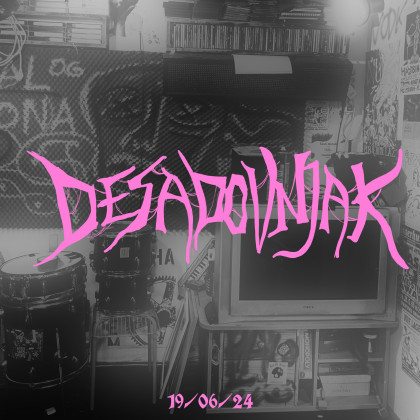 Slika z rožnatim logom Desadovnjak na črnobeli fotografiji sobe s televizijo.