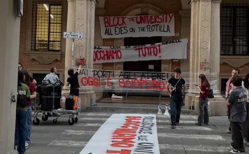 Slika vhoda v eno izmed stavb Univerze v Bologni čez vhod katere so na transparentih obešeni slogani študentske stavke.