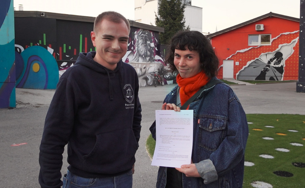 Slika prikazuje svetovalca predsesdstva ŠOU Kristijana Briškega in direktorico Radia Študent Valentino Rajaković med primopredajo spremenjenega Akta o ustanovitvi Zavoda Radia Študent, po 6. redni redni seji Študentskega zbora ŠOU.